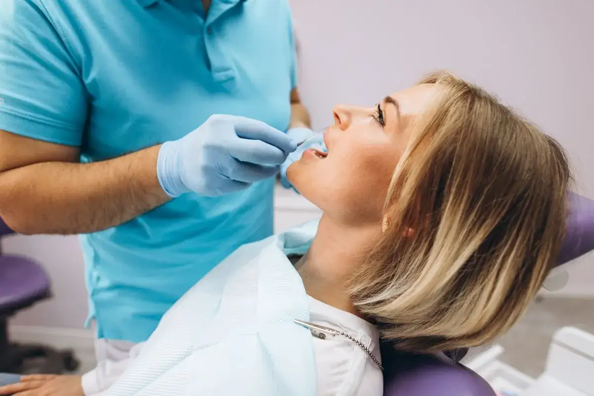 Dentysta bada zęby pacjentki, która cierpi na ból wszystkich zębów.
